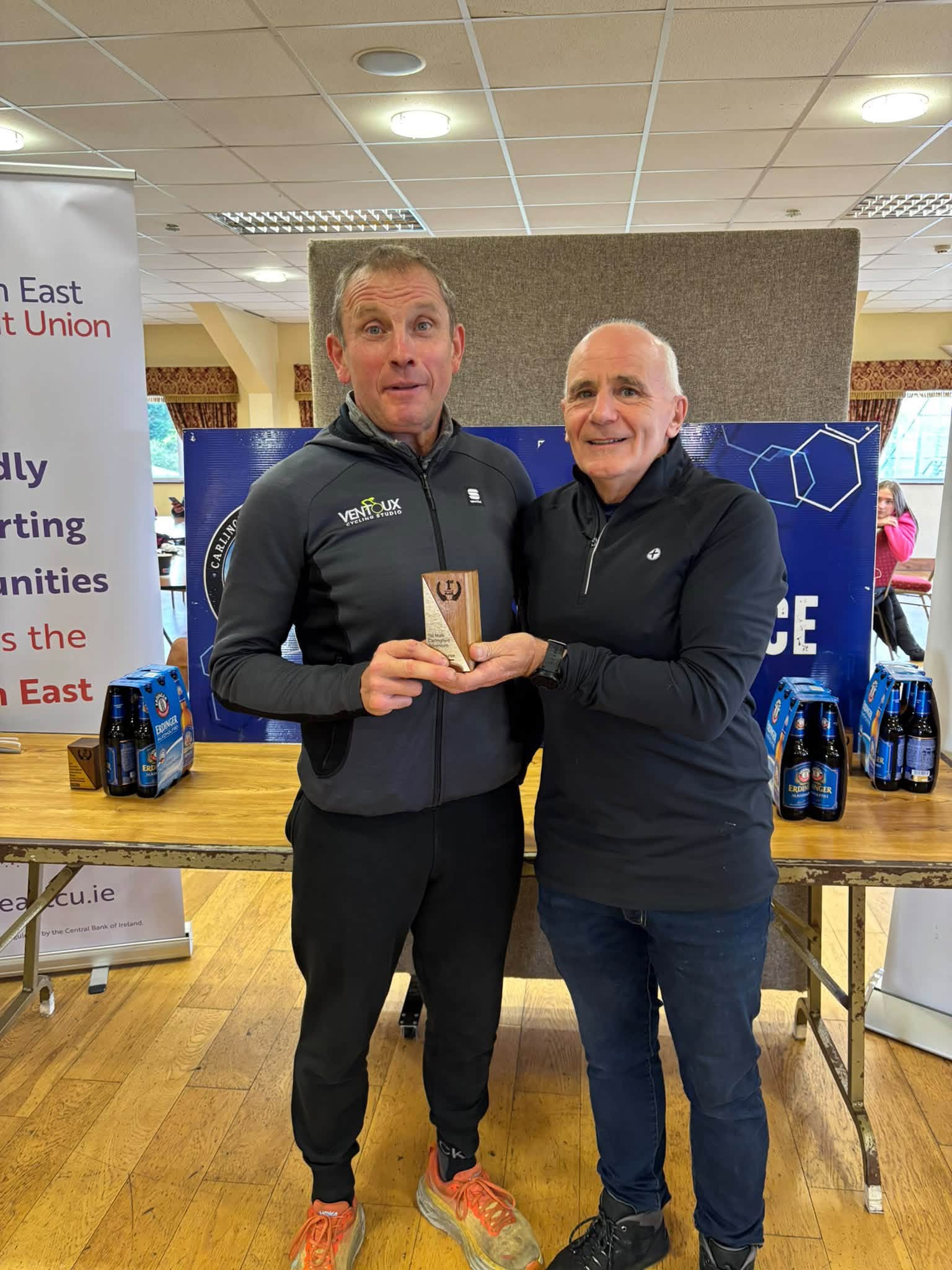 Prize giving: a winner in a grey zip top is presented with a trophy